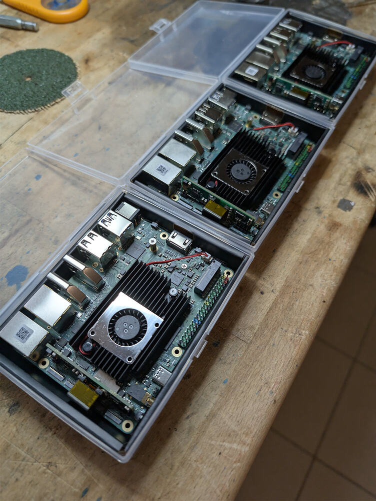 Three Rock 5T boards open on a workbench with small fans mounted over the heatsinks.