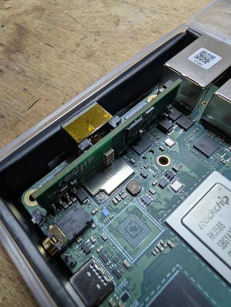 Close view of a Radxa Rock 5T board with the PoE module installed beside the Ethernet ports.